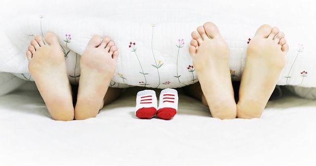 Stopy kobiety i mężczyzny leżących w łóżku i starających się o ciążę